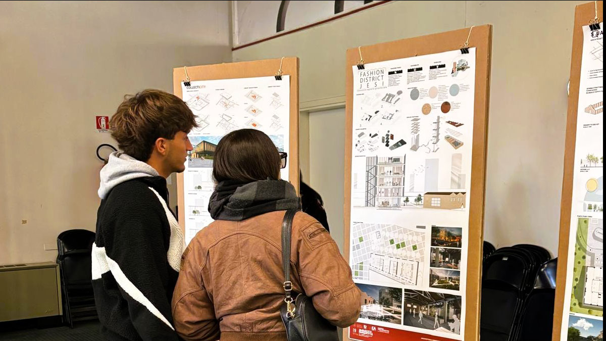 Uno studente e una studentessa davanti a un pannello della mostra allestita